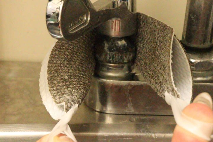 ダイソーのクリーナーを蛇口の根元に巻き付け、紐を引っ張って掃除している様子