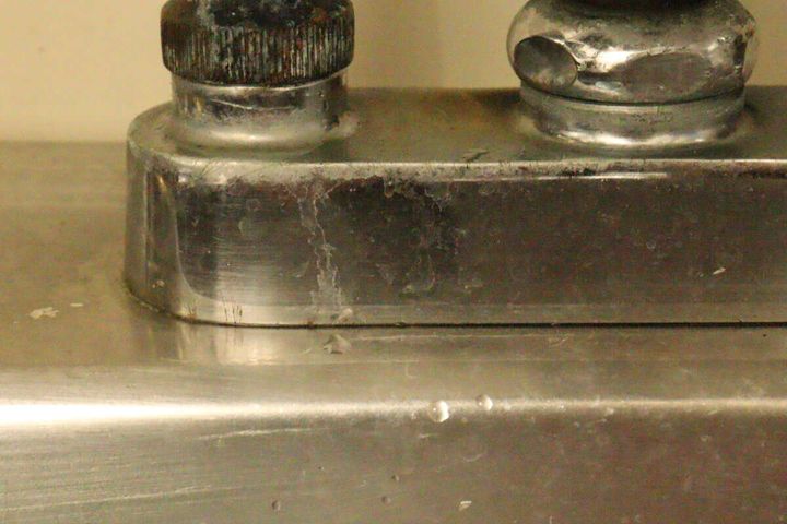水垢とサビがこびりついた状態の古い蛇口の根元部分