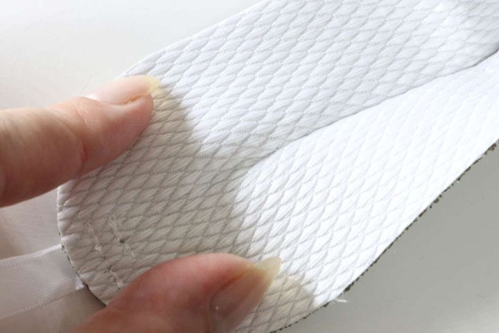 指で触って質感を確認しているダイソー蛇口の水垢落とし両面クリーナーの白い面