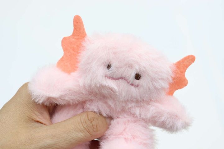 手のひらに乗せられたピンク色のウーパールーパー型シュシュの顔部分がアップで写っている