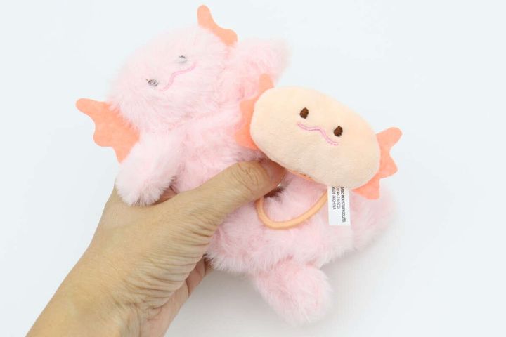 手のひらにピンク色のウーパールーパー型シュシュとベージュのウーパールーパー顔型ヘアゴムが重ねて持たれている