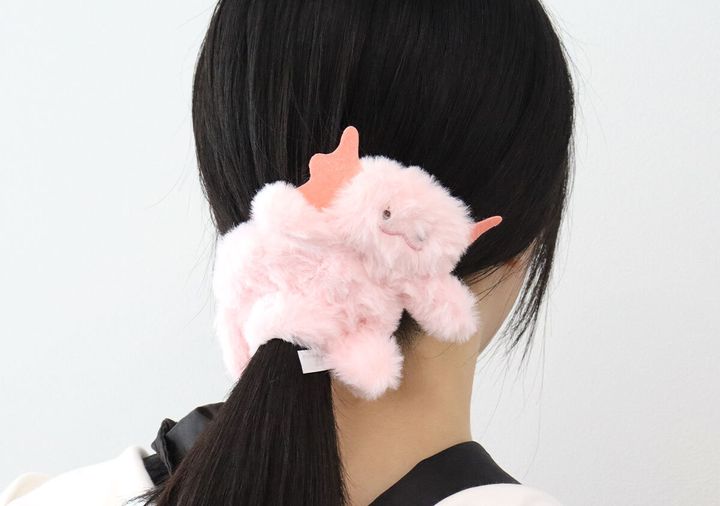 黒髪の女性がポニーテールにピンク色のウーパールーパー型シュシュを付けている後ろ姿