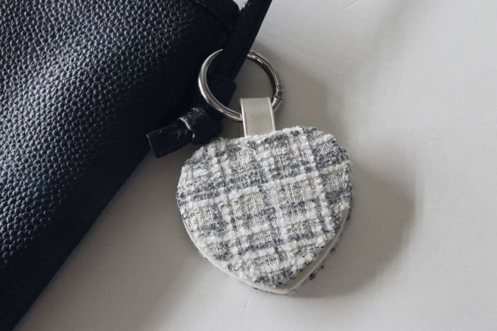 黒いショルダーバッグの持ち手にツイード素材のハート型マルチフックが取り付けられている