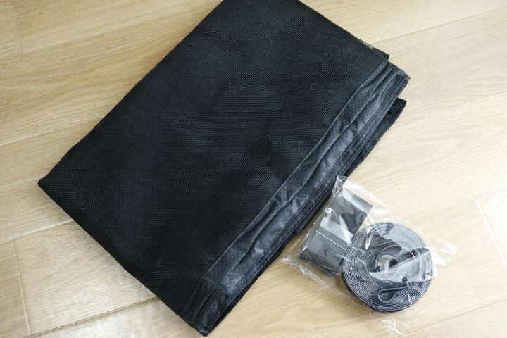 黒いマグネット式網戸ネットが畳まれ、面ファスナーなどの付属品が袋に入っている