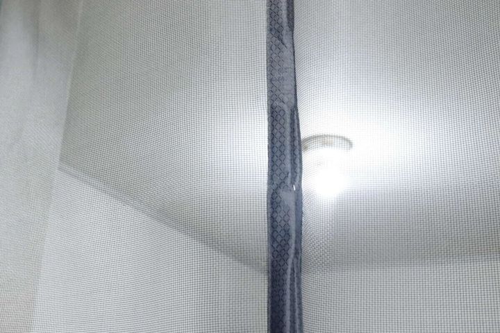 マグネットで閉じた網戸の中央部分、奥に部屋の明かりが見える
