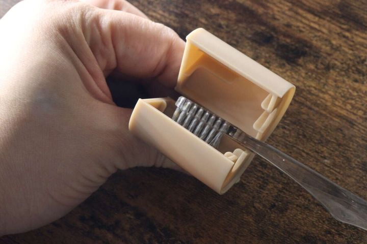 手の指で歯ブラシのヘッドをベージュのクリップに挟んでいる様子