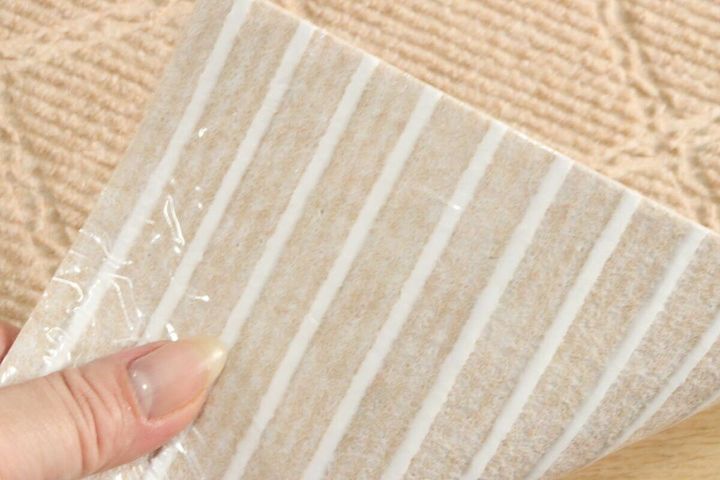 女性の指が吸着マットの裏面の保護フィルムを剥がしている様子