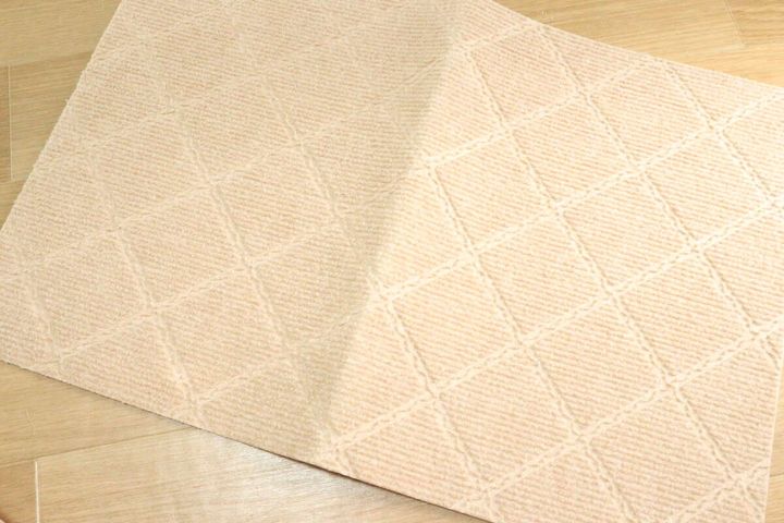 ベージュのダイヤ柄吸着マットが床に広げられ、中央が少しめくれている状態