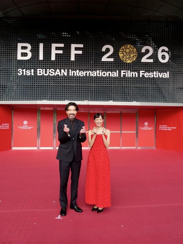 「BIFF」の大型ロゴをバックに、お茶目に指ハートを贈る柄本佑と石橋静河 [c] 2026 K2 Pictures