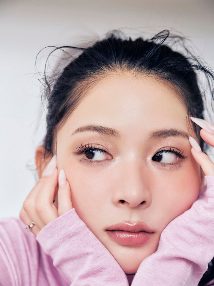 ピンクのタートルを着て頬に手をあてるモデルのミチ