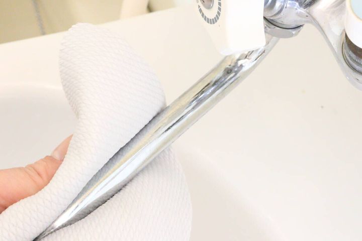女性の手がダイソーのクリーナーソフト面で蛇口を拭いてツヤを出している