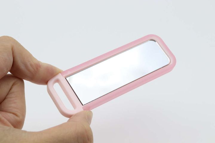 手で持ったピンク色の「こっそりミラー」の鏡面