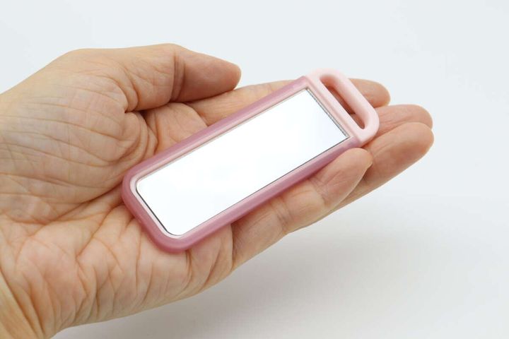 手のひらに乗せたピンク色の「こっそりミラー」