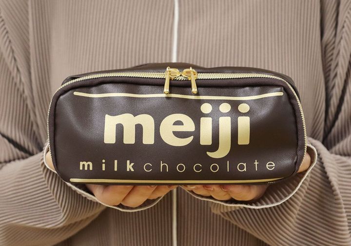 両手で持った明治ミルクチョコレートデザインのポーチ