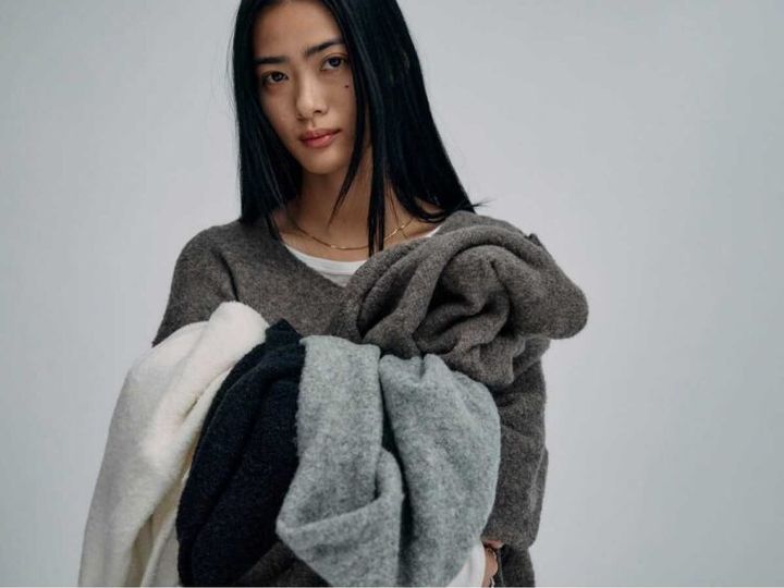 for/c p.mのヤク混ウールニットを着用し、色違いのニットを手に持つモデル