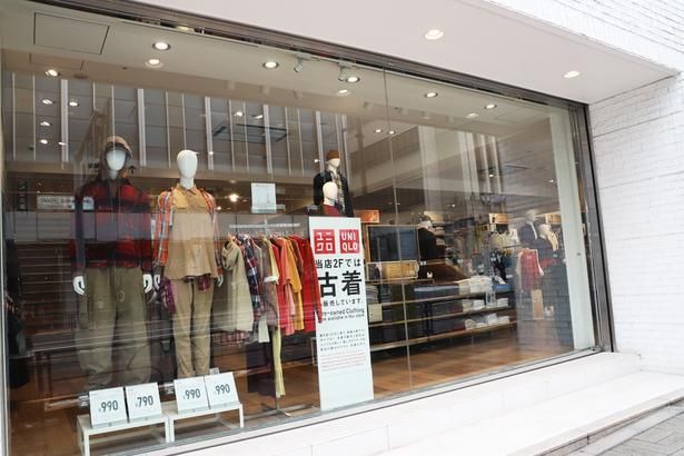 ユニクロ 新宿三丁目店のショーウィンドウ。2階に古着売り場があることを示す看板が設置されている