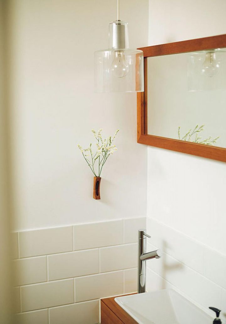 白を基調としたトイレの壁には、壁掛けの一輪挿しや、窓際に置いた鮮やかな色みの植物で彩りをとり入れて。