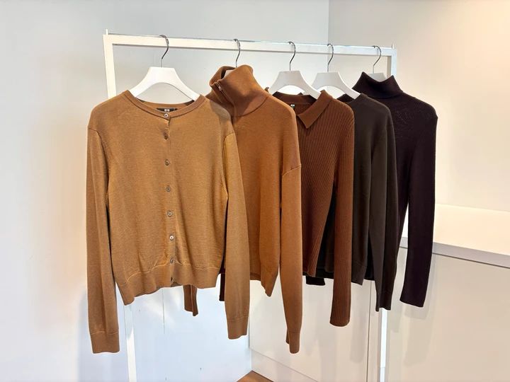 【UNIQLO（ユニクロ）】薄手ブラウンニット5枚を着比べ！秋は一枚、冬はインナーに使いやすいのは？＃BAILA比べる試着室 今回は「ユニクロの薄手ブラウンニット」5型を、身長162cmのライターが実際に着比べて徹底比較！ 「服が欲しいけれど、同じアイテムでも種類が多くて違いが分からない……」。売り場やオンラインストアで、そんなふうに迷ったことはありませんか？ 一見よく似たアイテムでも、比べてみると素材やシルエット、着こなしの印象は意外なほど違います。 そこで「比べる試着室」では、似ている人気アイテムを実際に着比べながら、それぞれの魅力や違いを検証。「どれが一番」という視点ではなく、「どんな人に合う一枚なのか」をレビューします。 10月に頼れるのが、一枚で秋らしく、冬にはインナーとしても使える薄手ニット。今回はユニクロからブラウン系5型をピックアップしました。同じ￥3990でもデザインや生地はさまざま。秋に一枚で着たいのか、冬の重ね着まで重視するのかを軸に比べます。 秋は一枚、冬は重ね着に。ユニクロの薄手ブラウンニット5型を比較！ 今回比べるのは、写真左から「メリノクルーネックカーディガン」「スムースコットンフルジップカーディガン」「3Dメリノブレンドリブポロセーター」「メリノクルーネックセーター」「メリノリブタートルネックセーター」の5型。価格はすべて￥3990、着用サイズはMです。カラーはブラウン系でそろえました。 うち2型は、前開きできるカーディガン。どこを基準にすると選びやすいのか、5型を着比べてくわしく見ていきましょう！ まずは結論を一覧でチェック！ ユニクロの薄手ブラウンニット5型はどう違う？ 5型は見た目だけでなく、一枚着、冬のインナー、羽織りと得意な着方にも違いがあります。まずは選び分けのポイントを一覧でチェック！ 【結論早見表挿入】 それぞれの違いを、まずは生地から詳しく見ていきましょう。 【生地を比較】フラットなメリノ、表情のあるリブ。ブラウンの色みも見比べ！ 5型を近くで比べてまず気づいたのが、同じ薄手のブラウンニットでも、生地の表情がかなり違うこと。 左から2番目の「メリノクルーネックセーター」といちばん左の「メリノクルーネックカーディガン」は、どちらも毛100％。編み目が細かく表面がすっきりしていて、光沢感のある端正な印象です。 同じ毛100％でも、いちばん右の「メリノリブタートルネックセーター」は細かなリブが入ることで印象が変化。縦に走る編み地の凹凸がはっきり見え、フラットなメリノ2型よりも生地そのものに表情があります。 中央の「3Dメリノブレンドリブポロセーター」はアクリル70％・毛30％のメリノブレンド。こちらもリブですが、先ほどのカーディガンより編み目が太いリブで、凹凸の存在感は強め。プレーンなメリノがすっきりキレイめに見えるのに対し、リブは編み地そのものが着こなしのポイントになります。 そして5型で唯一、綿100％なのが「スムースコットンフルジップカーディガン」（写真左から2番目）。ウール系4型とは表情が異なり、ファスナーのデザインも相まってよりカジュアル。同じ薄手ニットでも、素材と編み地だけでかなり印象が変わります。 生地を見比べると、もうひとつ気になるのがブラウンの色みです。今回は「ダークブラウン」と「ブラウン」があり、さらに同じカラー名でもカラー番号が異なります。 ダークブラウンは2型で、下写真左の「メリノクルーネックセーター」は38 、右の「メリノリブタートルネックセーター」は39のカラー番号。とくに後者は杢糸が使われているため、同じダークブラウンでも単色のクルーネックとは見え方がちょっと違います。リブの陰影も重なり、よりニュアンスのあるブラウンに。 一方ブラウンは3型。下写真左から「メリノクルーネックカーディガン」は34 、「スムースコットンフルジップカーディガン」と「3Dメリノブレンドリブポロセーター」は35。ダークブラウンの「メリノクルーネックセーター」（いちばん右）と比べても、この3型は明るく、より色みを楽しめるカラーです。 さらに秋に一枚で着るなら、肌当たりも気になるポイント。5型ともなめらかな肌あたりで着心地もよかったですが、タートルは首まわりまでニットが触れるため、チクチク感に敏感な人は薄手のインナーを一枚挟むのがおすすめです。 ちなみにお手入れはウール系4型が洗濯機可・ネット使用。「スムースコットンフルジップカーディガン」は手洗い可です。 【シルエットを比較】同じMサイズでもここまで違う！ 上半身の見え方をチェック 5型を同じMサイズで着比べて、まず差を感じたのが上半身のコンパクトさ。 基準にしやすいのは、いちばん左の「メリノクルーネックセーター」。体にぴったり沿いすぎず、大きくゆるすぎないベーシックなバランスで、ワイドパンツにもスカートにも合わせやすいシルエットです。 いちばん右の「メリノリブタートルネックセーター」と中央の「3Dメリノブレンドリブポロセーター」は、どちらもリブが体に沿い、クルーネックより上半身がコンパクト。ワイドパンツやフレアスカートなど、ボリュームのあるボトムともバランスを取りやすい2型です。 カーディガン2型は、前を閉じた状態だけでなく、開けたときの変化まで見たいところ。 H 右の「スムースコットンフルジップカーディガン」は、ファスナー自体に存在感があり、ほか4型よりカジュアルな印象。前を開けるとインナーがしっかり見え、フロントに縦のラインが生まれるので、羽織りとしても使いやすいデザインです。一方、ボタンタイプの「メリノクルーネックカーディガン」は、前を開けてもファスナータイプよりすっきりとした印象。同じ前開きでも、ボタンならキレイめ、ファスナーならカジュアルと、着こなしの雰囲気にも違いが出ました。 一枚で着たときの形を重視するならプルオーバー、インナーとのレイヤードや羽織りとしての着こなしまで楽しみたいならカーディガン。Mサイズという条件は同じでも、デザインや身幅、体への沿い方によって上半身の見え方はかなり変わります。 【襟もとを比較】丸首、タートル、ポロで顔まわりの印象はどう変わる？ 同じブラウンニットでも、見比べると顔まわりに見える“ブラウンの分量”がかなり違いました。 最もシンプルなのは上から2番目の「メリノクルーネックセーター」。装飾のない丸首で、首まわりに適度な抜けがあります。ネックレスを合わせたりジャケットを重ねたりしてもデザインがぶつかりにくく、顔まわりをすっきり見せたい日に使いやすい一枚です。 顔まわりまでブラウンの存在感をしっかり出せるのがいちばん上の「メリノリブタートルネックセーター」。首を覆うぶん、丸首より秋冬らしいムードが高まりました。髪をまとめたときにもタートルがポイントになり、寒くなればジャケットやクルーネックトップスの中から首もとだけ見せる着方もできます。 中央の「3Dメリノブレンドリブポロセーター」は、首を覆うのではなく襟で顔まわりにポイントをつくるタイプ。ネックレスなどを足さなくてもトップスだけで着映えするので、シンプルなワンツーコーデにも向いています。 「スムースコットンフルジップカーディガン」は、ファスナーの位置で首もとの印象を変えられるのが特徴。上まで閉じればコンパクトに、少し下げれば肌やインナーが見えて抜けが出ます。襟を立てるか倒すかでもアレンジが効くのも嬉しいですね。 顔まわりをシンプルに見せるクルーネック、首もとまでブラウンを効かせるタートル、襟をポイントにするポロ、開け方で抜け感を変えられるフルジップ。同じブラウンでも、顔まわりにどんな印象をつくりたいかで選ぶ一枚が変わります。 【着回しを比較】一枚着、羽織り、冬のインナー。5型はどう使い分ける？ 最後は、秋から冬までの着回しを比較します。 今回の5型はどれも薄手ですが、デザインによって得意な着方は異なります。10月は一枚で着るのか、羽織りとして使うのか。さらに寒くなったら、アウターの中でどう生かせるのか。季節が進んだときの使い方まで考えてみましょう。 まず、一枚で着たときに最もベーシックなのが、やっぱり「メリノクルーネックセーター」（いちばん左）。装飾のないクルーネックなので、パンツにもスカートにも合わせやすく、通勤から休日まで着こなしを大きく限定しません。秋は一枚、寒くなればジャケットやコートの中へと、そのまま使い方をつなげやすいタイプです。 一枚で着たときにもう少しデザインを効かせたいなら、中央の「3Dメリノブレンドリブポロセーター」。リブとポロ襟がポイントになるので、シンプルなボトムとのワンツーコーデでもトップスに存在感が出ます。 いちばん右の「メリノリブタートルネックセーター」は、首もとまでブラウンが見えることで一枚でも秋冬らしい印象。さらに季節が進めば、タートル部分を見せるレイヤードへと着方を広げられます。 一方、プルオーバー3型にはない着方ができるのがカーディガン2型です。 「メリノクルーネックカーディガン」は、ボタンを閉じれば薄手ニット感覚、開ければキレイめな羽織りに。10月ならTシャツやシャツの上に重ねるだけで、朝晩の気温差にも対応しやすくなります。一枚のトップスとしても羽織りとしても使いたい人には、この前開きできるデザインが大きな選択ポイントです。 「スムースコットンフルジップカーディガン」も、ファスナーを開ければ羽織りとして使えるタイプ。メリノカーディガンよりカジュアルな印象なので、休日にTシャツなどと重ねたい人はこちらが候補になります。 さらに冬になると、薄手ニットの使い道はアウターの中へ。 冬のインナーとしてとくにデザインを生かしやすいのが「メリノリブタートルネックセーター」。ジャケットやコートを重ねても首もとのブラウンが見えるので、アウターを着た状態でもニットの存在感が残ります。 一方「メリノクルーネックセーター」もインナーに使いやすいタイプですが、こちらは逆に襟もとを主張しすぎないのが持ち味。ジャケットやコートの中にすっきり合わせたいときに使いやすいです。 カーディガンも、前を閉じれば冬はトップス感覚でアウターの中へ。「メリノクルーネックカーディガン」なら、秋は羽織り、冬はボタンを留めてインナーと、季節によって役割を変えられます。 一枚で幅広く着回すならクルーネック、冬のレイヤードを楽しむならタートル、一枚で着映えさせたいならポロ、羽織りとトップスを兼ねたいならカーディガン。今の着方だけでなく、寒くなったときにどう使いたいかまで考えると、自分に合う一枚がさらに選びやすくなります。 ユニクロの薄手ブラウンニット5型、どんな人におすすめ？ 5型を着比べると、同じブラウン、同じ￥3990でも「秋冬のワードローブで任せたい役割」はかなり違いました。最後に、それぞれどんな人におすすめなのかをまとめます。 一枚着もキレイめな羽織りも欲しいなら「メリノクルーネックカーディガン」（￥3990） ボタンを留めれば薄手ニット、開ければカーディガン。端正なメリノの生地で、羽織りとしてもキレイめにまとまります。秋の気温調節から冬のトップス使いまで、通勤を中心に長く着回したい人におすすめです。 「メリノクルーネックカーディガン」の商品ページはこちら https://www.uniqlo.com/jp/ja/products/E469411-000/00?colorDisplayCode=34&sizeDisplayCode=004 休日にカジュアルに着回したいなら「スムースコットンフルジップカーディガン」（￥3990） 5型で唯一の綿100％かつフルジップ。閉じればトップス、開ければ羽織りになり、ファスナーの位置でも首もとの印象を変えられます。キレイめなメリノとは違う、スポーティでカジュアルなブラウンニットを探している人に。 「スムースコットンフルジップカーディガン」の商品ページはこちら https://www.uniqlo.com/jp/ja/products/E487005-000/00?colorDisplayCode=35&sizeDisplayCode=004 一枚で着映える薄手ニットが欲しいなら「3Dメリノブレンドリブポロセーター」（￥3990） リブ編みとポロ襟が着こなしのポイントになり、シンプルなボトムを合わせるだけでも完成度が上がる一枚。秋は主役トップスとして、冬は襟を生かしたジャケットインに。丸首ニットとは違う変化が欲しい人の候補です。 「3Dメリノブレンドリブポロセーター」の商品ページはこちら https://www.uniqlo.com/jp/ja/products/E485321-000/00?colorDisplayCode=35&sizeDisplayCode=004 オンオフ着回せる王道ニットが欲しいなら「メリノクルーネックセーター」（￥3990） プレーンなメリノの生地にベーシックなクルーネック。5型の中でも合わせるボトムやアウターを限定しにくく、10月の一枚着から冬のジャケットインまで自然に移行できます。仕事にも休日にも使える薄手ニットを一枚選びたい人に。 「メリノクルーネックセーター」の商品ページはこちら https://www.uniqlo.com/jp/ja/products/E469410-000/00?colorDisplayCode=38&sizeDisplayCode=004 冬のレイヤードまでしっかり使いたいなら「メリノリブタートルネックセーター」（￥3990） 細身のリブとタートルネックで、一枚着から重ね着まで活躍。秋はすっきり一枚で、冬はジャケットやシャツの中から首もとを見せて。肌当たりが気になる日は薄手のインナーを挟みながら、冬まで長く着たい人に向いています。 「メリノリブタートルネックセーター」の商品ページはこちら https://www.uniqlo.com/jp/ja/products/E450514-000/00?colorDisplayCode=39&sizeDisplayCode=004 10月は一枚でブラウンを主役に、秋が深まったら羽織りやレイヤード、冬はアウターの中へ。同じ薄手ニットでも、クルーネック、タートル、ポロ、カーディガンでは季節が進んだときの使い方まで変わります。 今の着こなしだけでなく、冬にどんな役割を任せたいかまで想像しながら、自分に合う一枚を選んでみてください。 ディスクリプション ユニクロの薄手ブラウンニット5型を着比べ！「メリノクルーネックセーター」「メリノリブタートルネックセーター」ほか、生地や色み、シルエット、襟もとを比較。秋の一枚着から冬のインナー、羽織りまで選び方を紹介します。