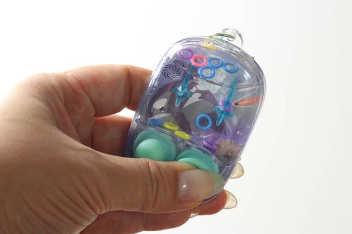 水が満たされ、輪っかが浮いているミニウォーターゲーム機を手に持っている