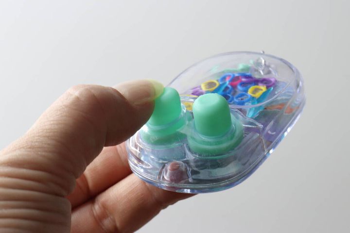 指でミニウォーターゲーム機の水色のボタンを押し、水流を起こしている
