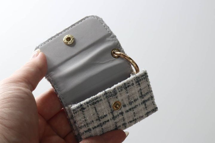 女性の指がイヤホンケースの蓋を開け内側のピーチスキン素材を見せている