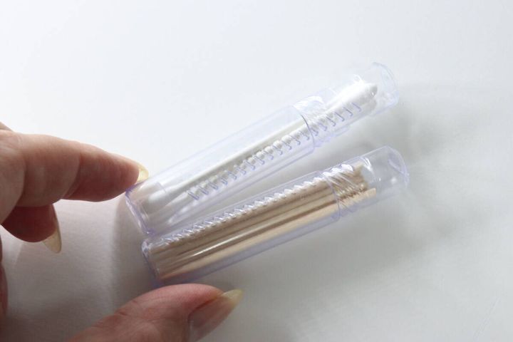 綿棒とつまようじがそれぞれ入ったスクリューケース2本を指でつまんで見せている