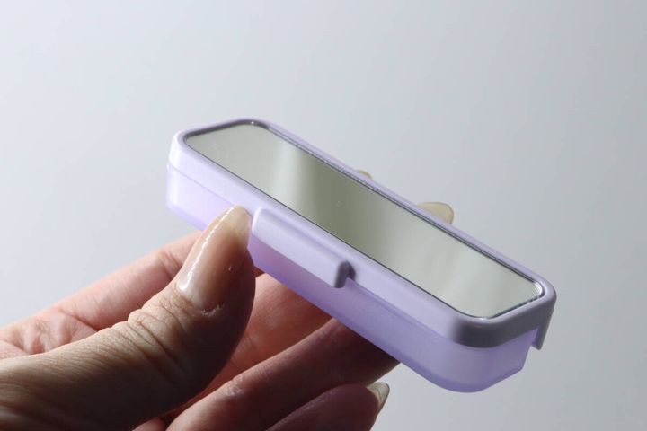 女性の指が、紫色の「ちょこっとケース ミラー付き」を横から持っている様子