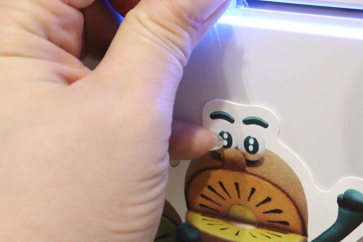 壁に貼られたポスターを剥がすため、テープのタブを引っ張って伸ばしている