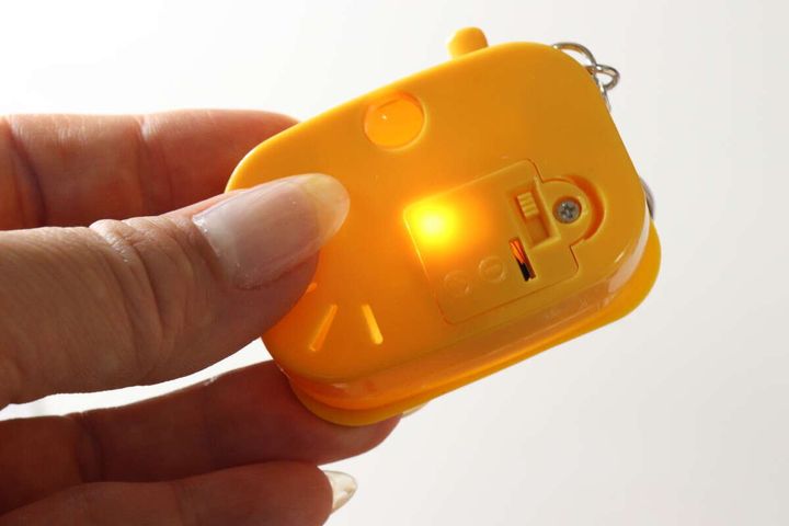カメラ型キーホルダーの裏側。絶縁シートを抜いた後、ライトが明るく点灯している。
