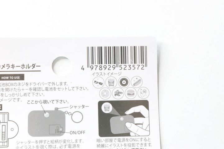 セリアのカメラ型キーホルダーのパッケージ裏面。バーコードと使用方法のイラスト説明。
