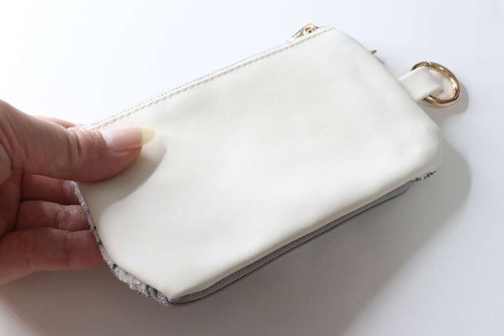 女性の指が、ポーチの裏面の白い合皮素材を触っている様子
