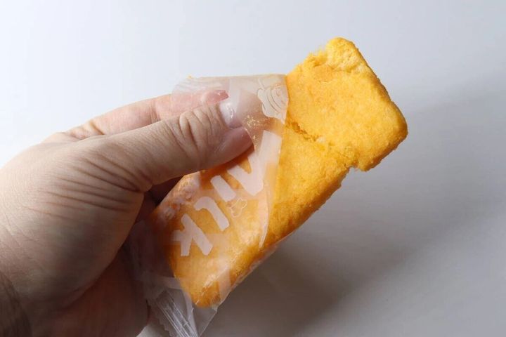 手がチーズ味ライスクラッカーの個包装を開けている