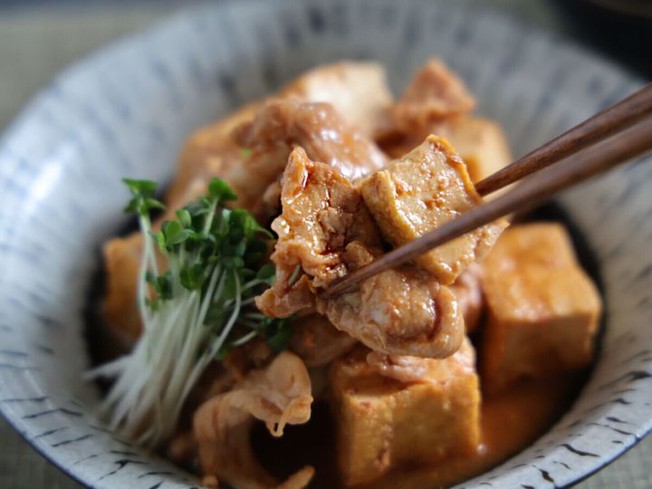 盛り付けられた韓国風厚揚げ肉豆腐を箸でつまみ上げているクローズアップ