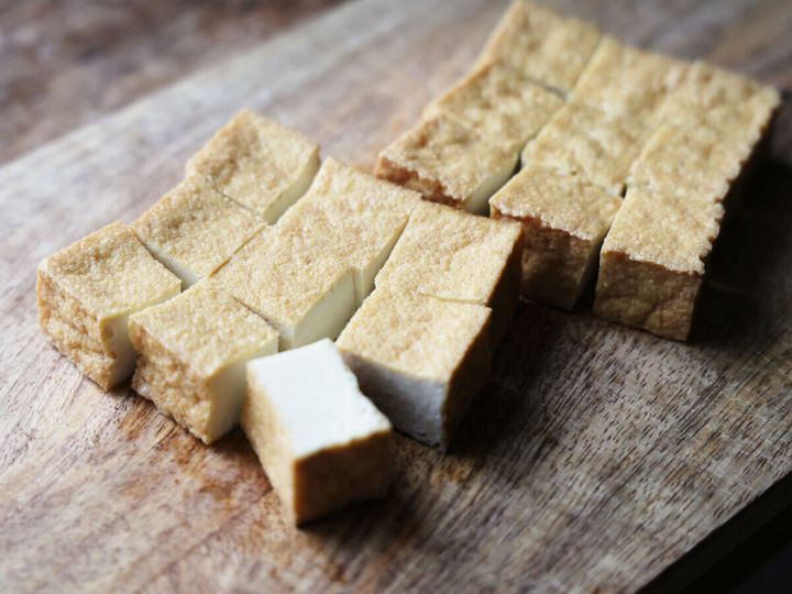 木製のまな板の上で厚揚げを9等分に切っている様子
