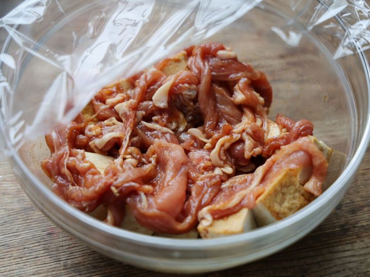 厚揚げと豚肉が入ったボウルにラップをかけ、電子レンジ加熱の準備をしている
