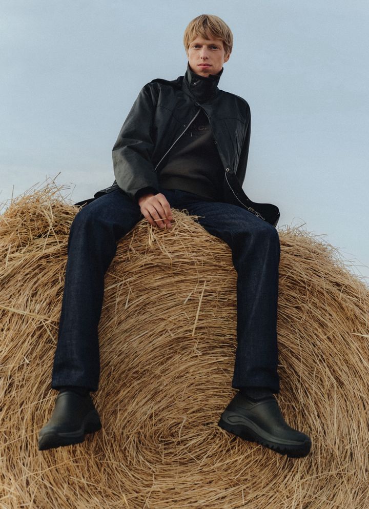 A.P.C. Barbourのビジュアル。干し草の上に座るモデル