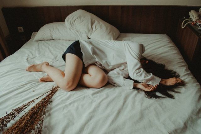ベッドの上で落ち込む女性