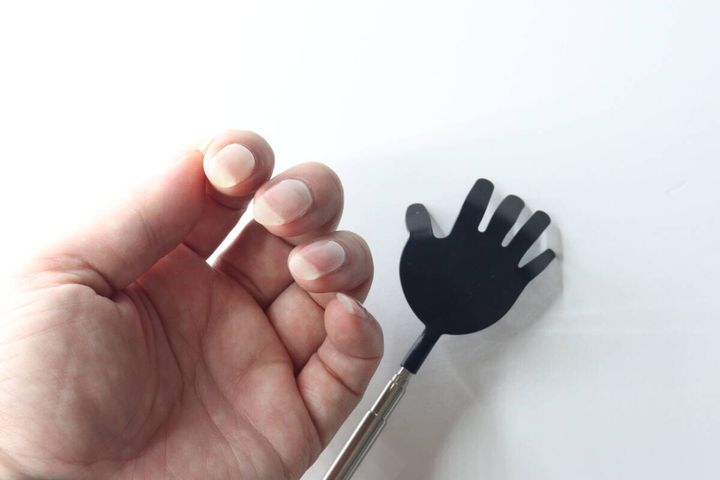 伸びた爪の指と、その横に置かれたダイソーの孫の手の先端部分