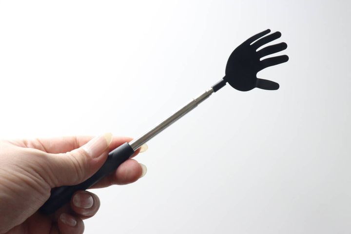 女性の手がダイソーの孫の手の持ち手を握り、少し伸ばしている様子