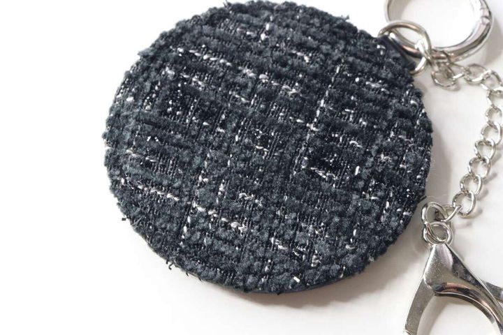 ツイード柄の黒い丸型鏡キーホルダーの表面をクローズアップした様子