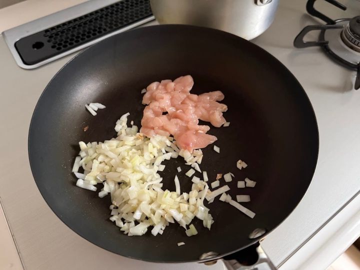 玉ねぎに鶏むね肉を加えて炒める