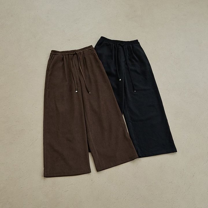 茶色と黒のウエストゴムのイージーパンツが床に並べられている俯瞰
