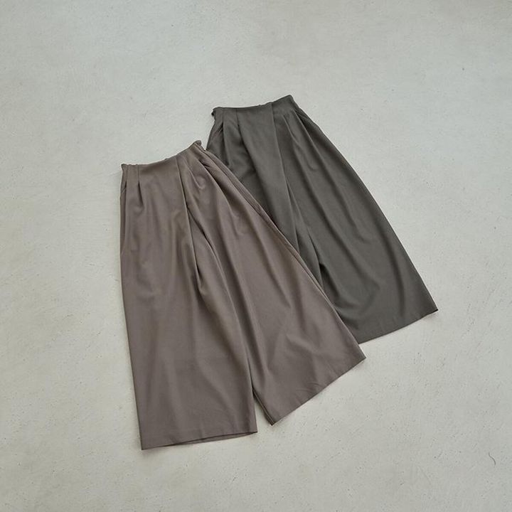 ベージュとグレーのラップ風ワイドパンツが床に並べられている俯瞰