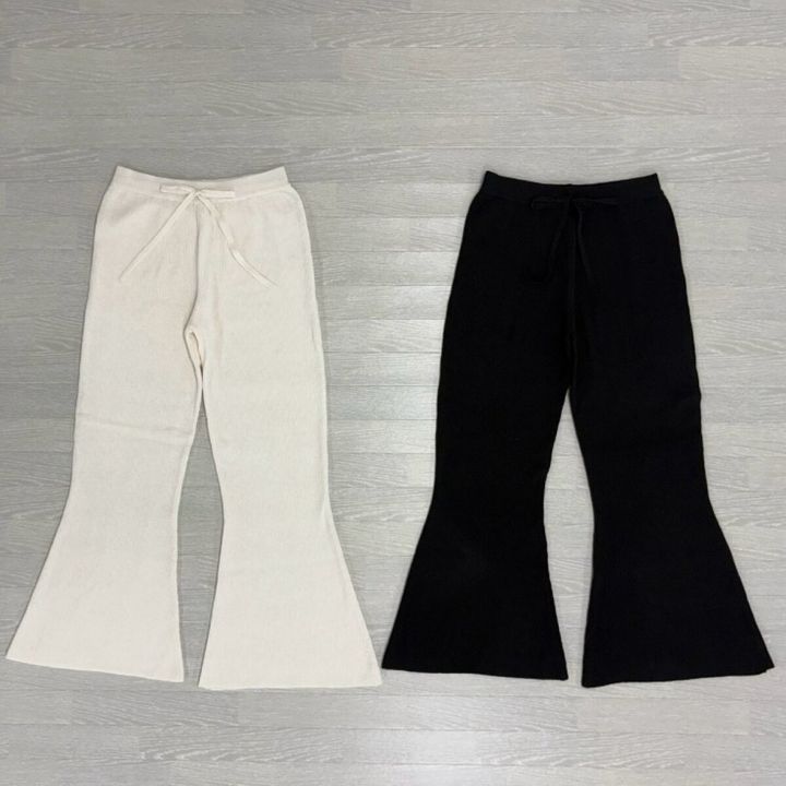 白と黒のウエスト紐付きニットフレアパンツが床に並べられている俯瞰