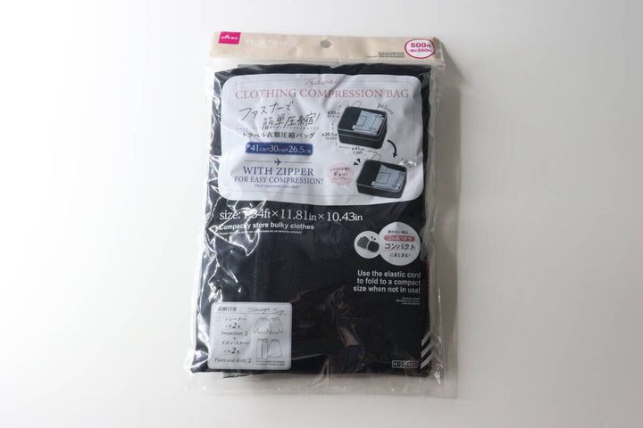 透明なパッケージに入った黒いトラベル衣類圧縮バッグ。商品名やサイズ、収納目安が記載されている。