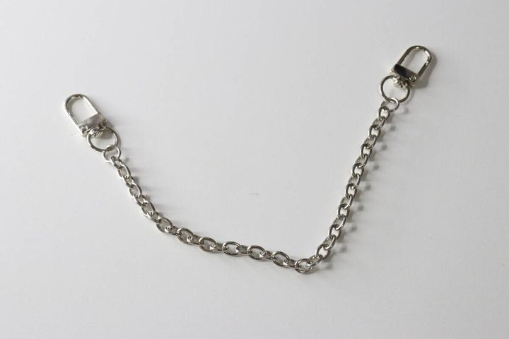 白い背景に置かれた、両端にナスカンフックが付いた銀色のチェーン