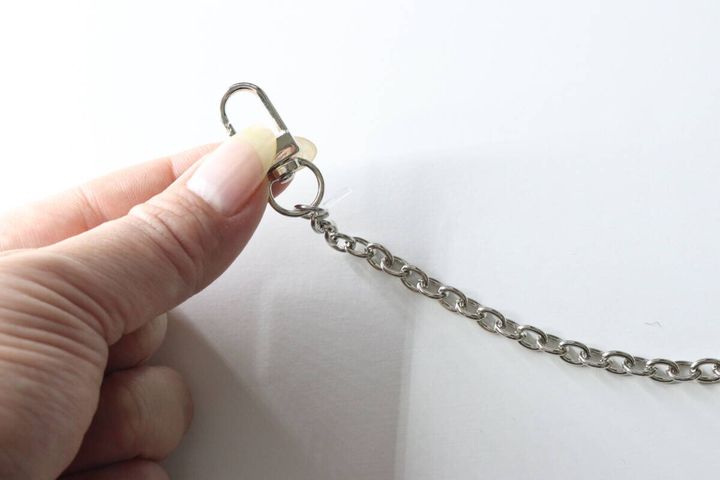 人差し指と親指で銀色のナスカンフックを開閉している様子
