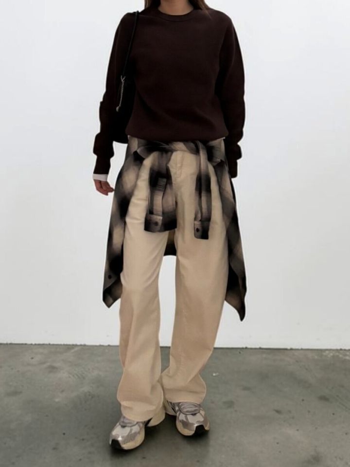 ベージュのバレルパンツにブラウンニットとチェックシャツ腰巻きのこなれ感ある女性の全身コーデ