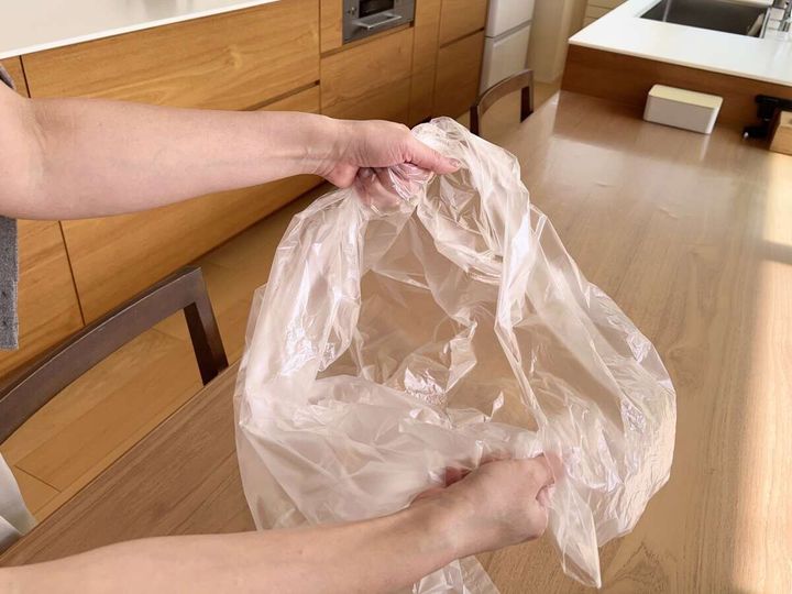 女性が透明なゴミ袋を両手で広げている様子