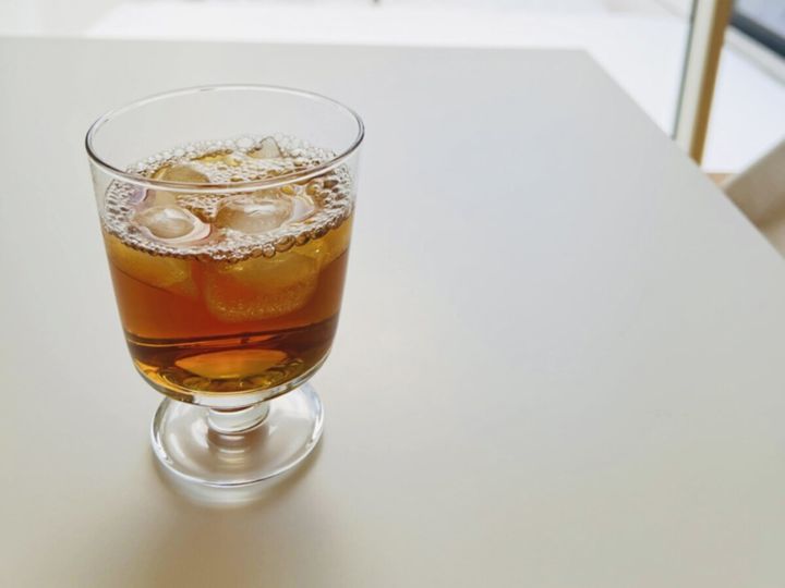 氷と泡が入ったグラスの飲み物が白いテーブルに置かれている